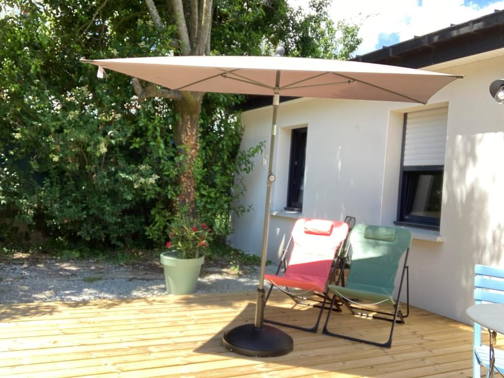 an umbrella and two chairs on a deck at Petite maison ensoleillée à 10 minutes du port de Vannes in Vannes