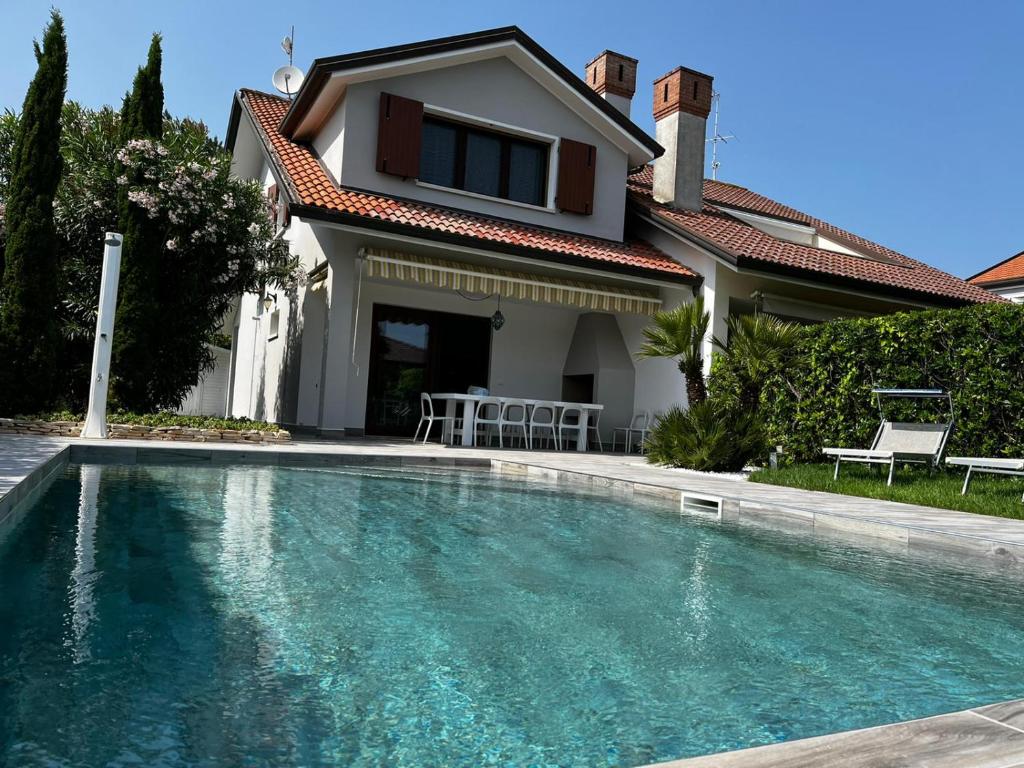 a house with a swimming pool in front of a house at VILLA SALICE 9.2 in Isola Albarella