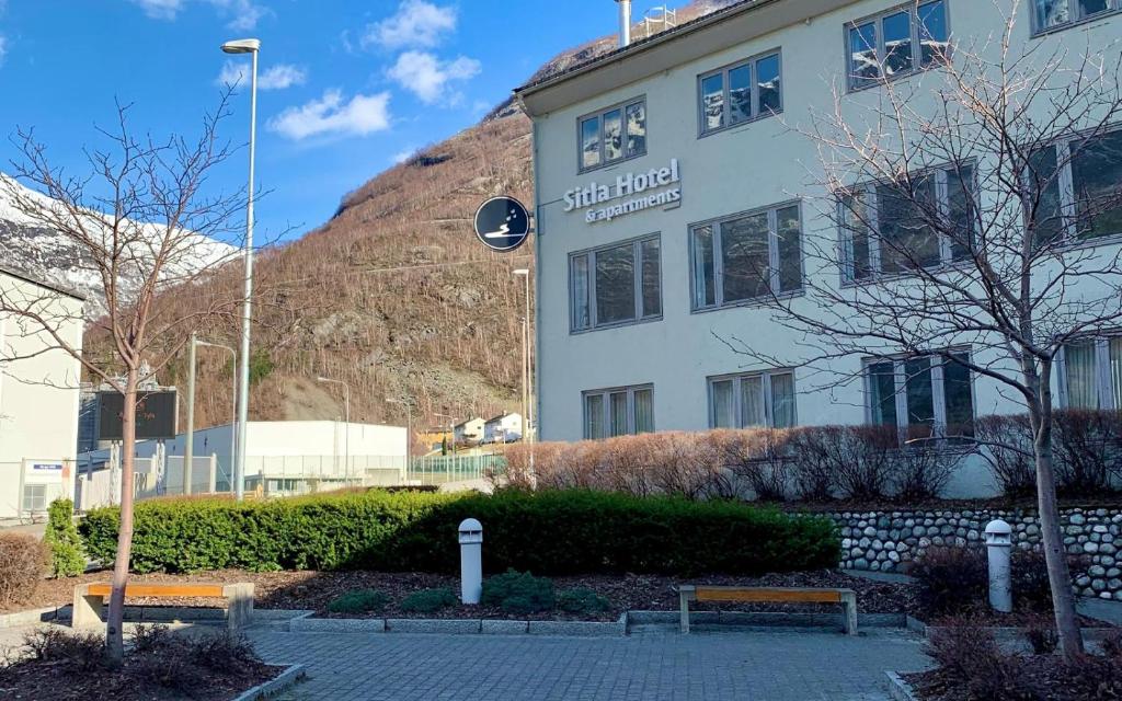 a building in front of a mountain with two benches at Sitla Hotel & Appartments in Øvre Årdal