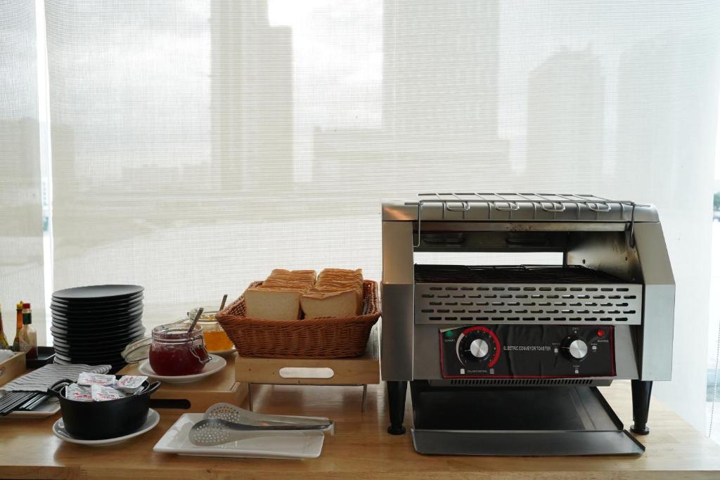 A breakfast counter provides a toaster oven, bread, jam, cups, and plates beside bright windows.