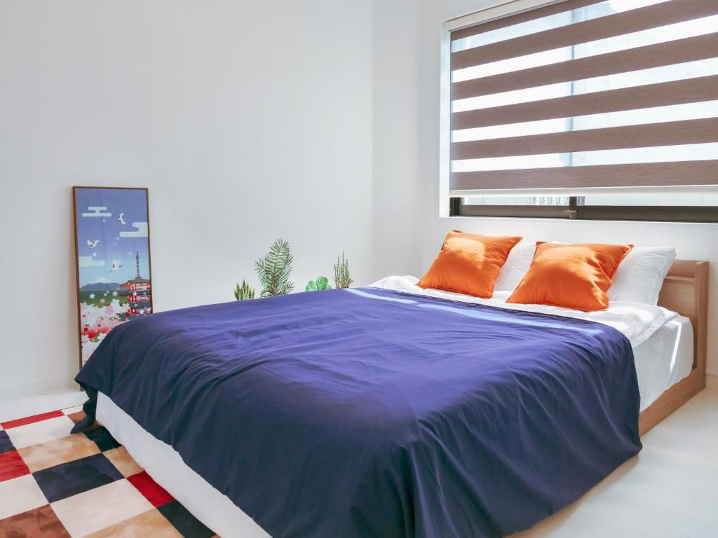 ein Schlafzimmer mit einem Bett mit orangefarbenen Kissen und einem Fenster in der Unterkunft 2023 Open Shinjuku Okubo 5mins to 2stns 200M WIFI in Tokio