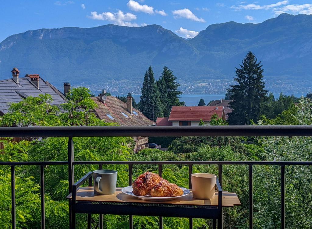 une table avec une assiette de nourriture sur un balcon dans l'établissement L'Écrin Vue Lac 3 étoiles - Parking gratuit, Calme & confort, à Sévrier
