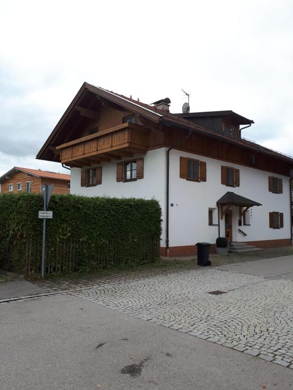 a white house with a wooden roof at Nabo Ferienwohnung Lechbruck in Lechbruck