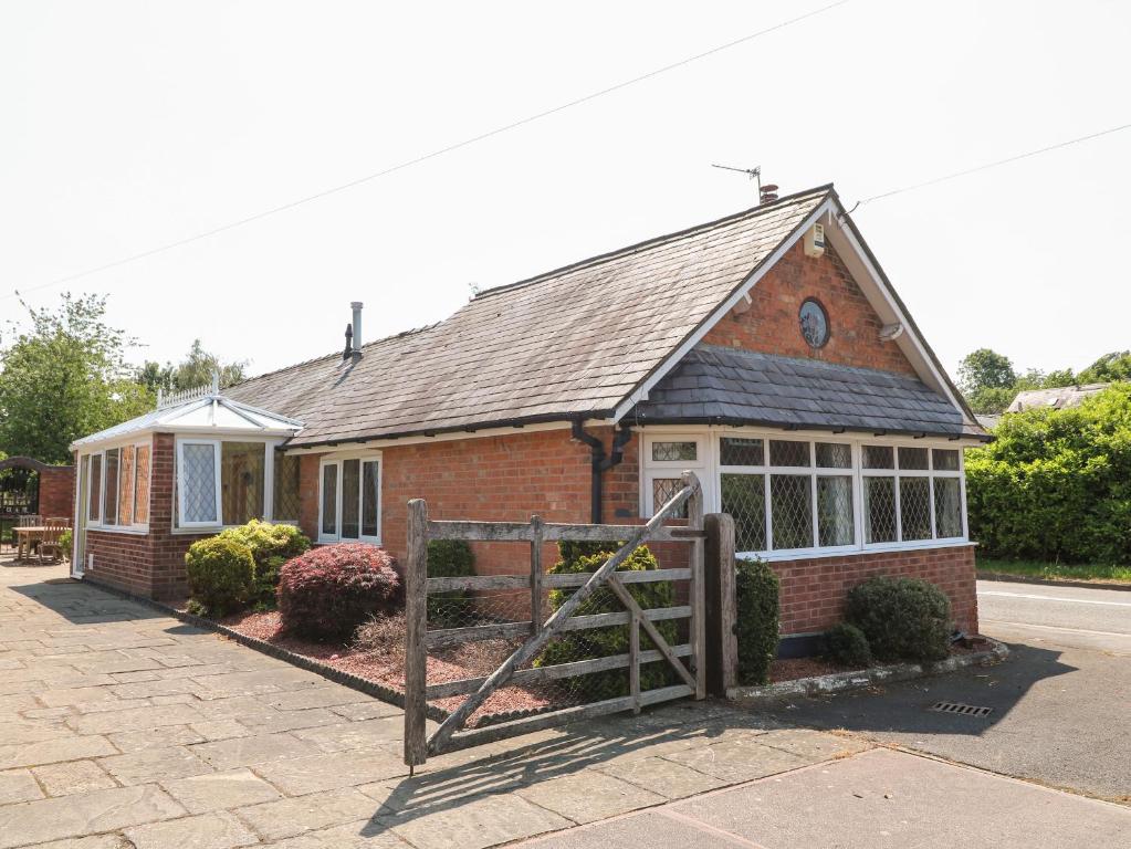 a small brick house with a gate in front of it at Elm Tree Cottage in Melton Mowbray