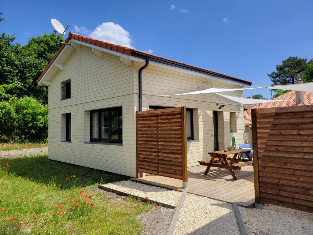 une maison avec une terrasse en bois et une table dans l'établissement Les Cabanes de l'Airial Dune, à Andernos-les-Bains