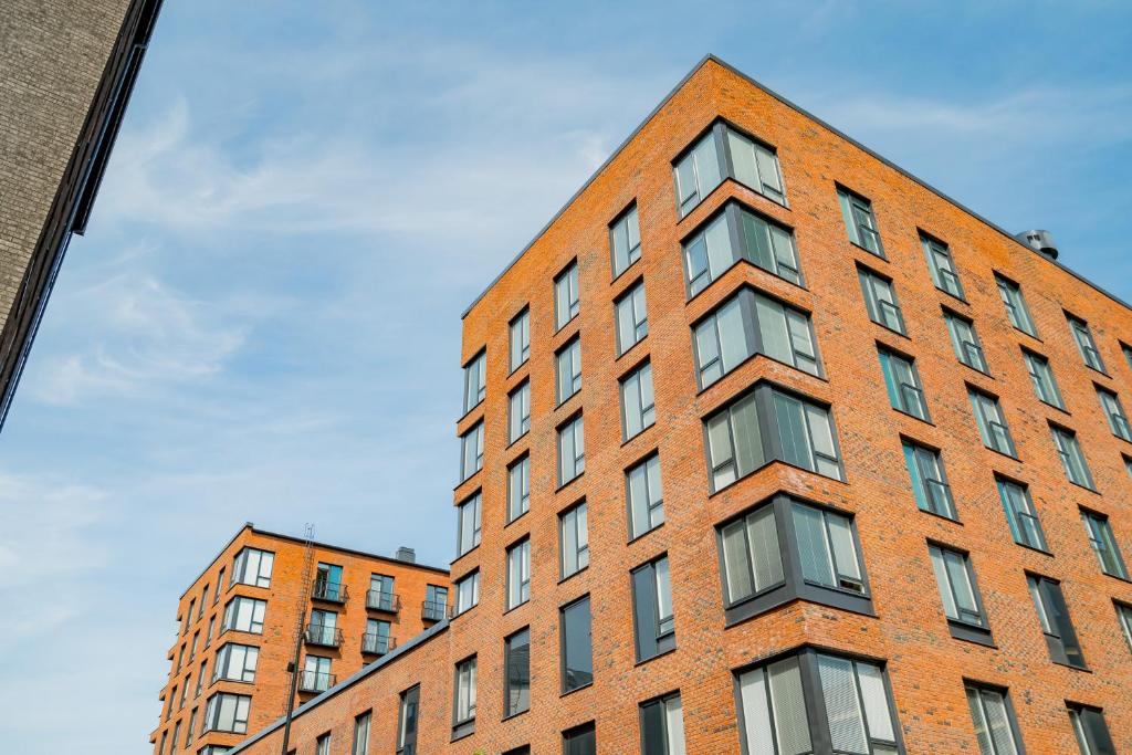 a tall orange brick building with windows on it at Hiisi Homes Turku Herttuankulma in Turku