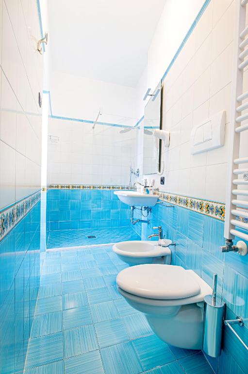 a blue bathroom with two toilets and a sink at Hotel Villa Pandora in Maiori