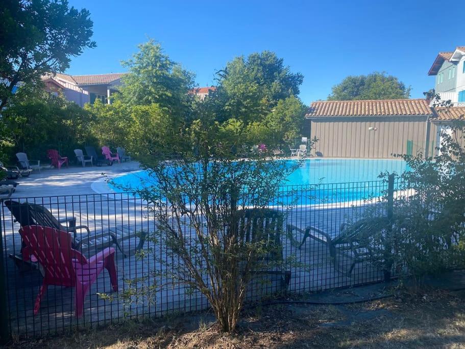 une clôture avec des chaises à côté d'une piscine dans l'établissement residence les rives marines bassin d arcachon, au Teich