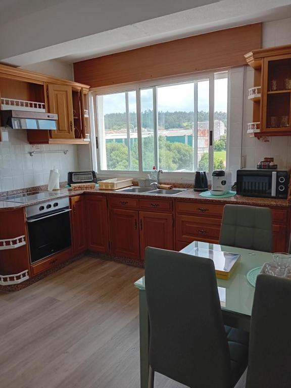 une cuisine avec des placards en bois et une grande fenêtre dans l'établissement Milladoiro, à Teo