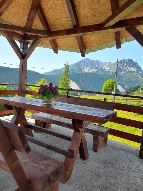 a wooden picnic table with a view of mountains at DURMITOR APARTMAN Pitomine in Žabljak
