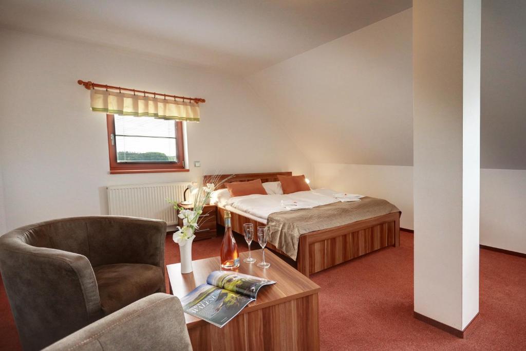 sypialnia z łóżkiem, krzesłem i stołem w obiekcie Golf&Wellness Resort Alfrédov w mieście Alfrédov