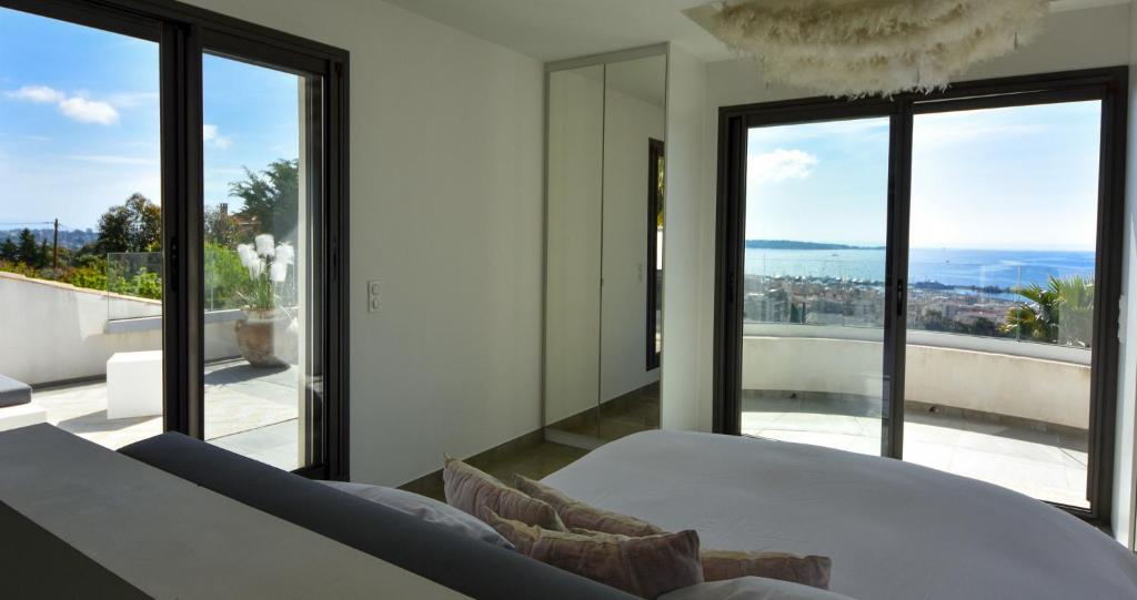 a bedroom with a bed and large glass windows at Séjour de Luxe à Golfe Juan, 15 mn de Cannes in Vallauris