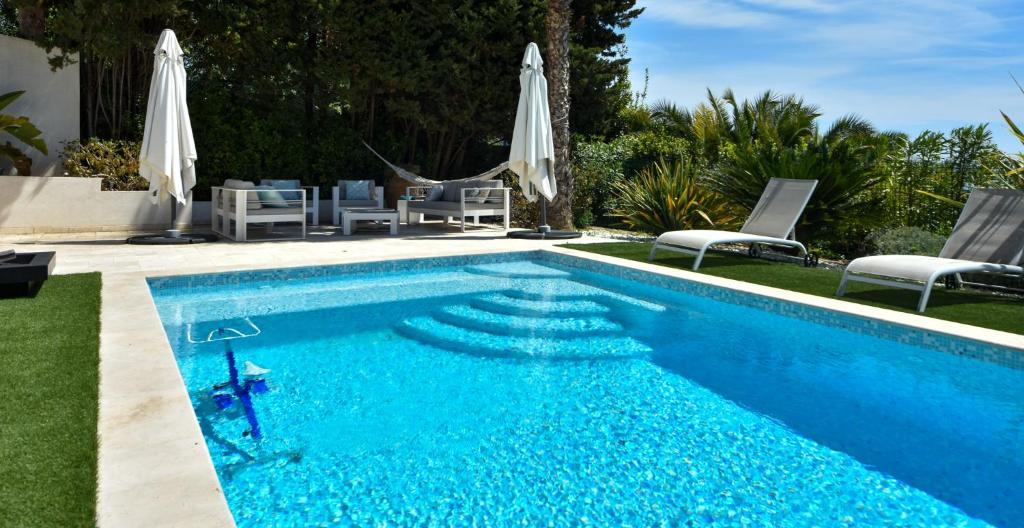 a swimming pool with chairs and umbrellas at Séjour de Luxe à Golfe Juan, 15 mn de Cannes in Vallauris