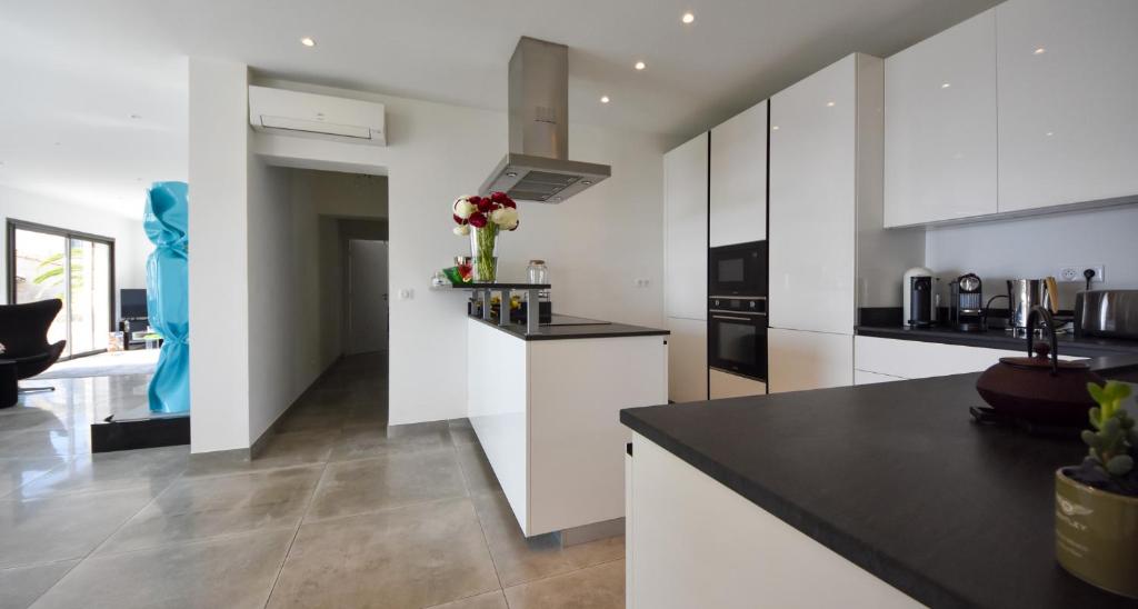 a kitchen with white cabinets and a black counter top at Séjour de Luxe à Golfe Juan, 15 mn de Cannes in Vallauris