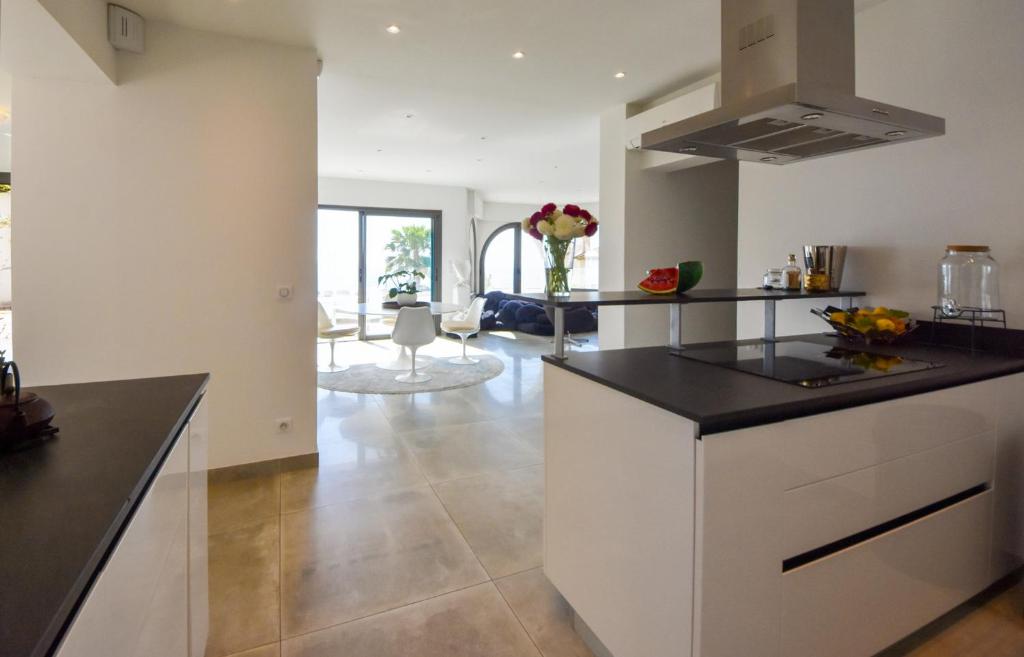 a kitchen with white cabinets and a black counter top at Séjour de Luxe à Golfe Juan, 15 mn de Cannes in Vallauris