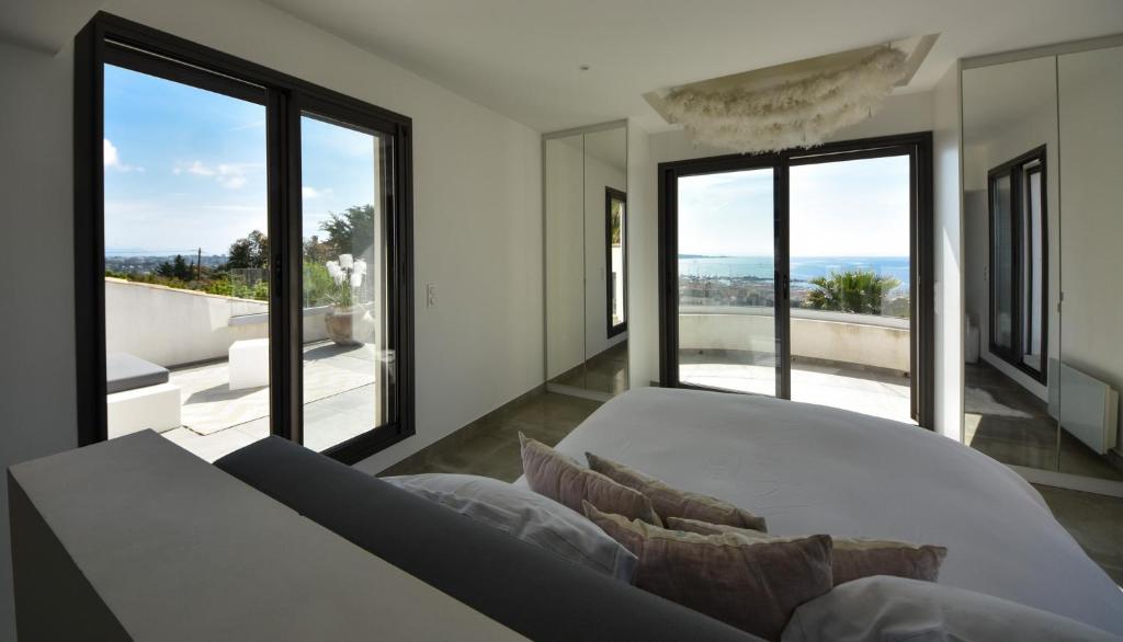 a bedroom with a large bed and large windows at Séjour de Luxe à Golfe Juan, 15 mn de Cannes in Vallauris
