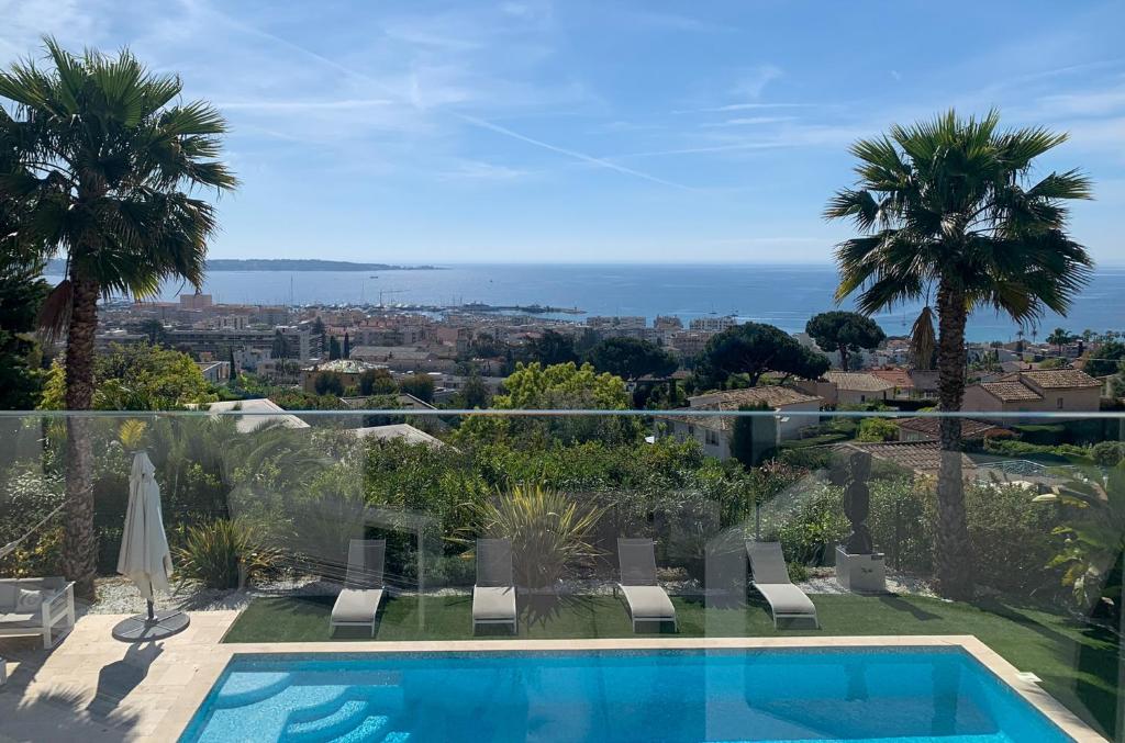 a villa with a swimming pool and palm trees at Séjour de Luxe à Golfe Juan, 15 mn de Cannes in Vallauris
