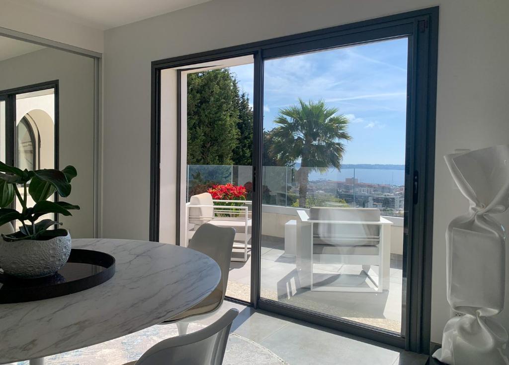 a dining room with a table and a large glass window at Séjour de Luxe à Golfe Juan, 15 mn de Cannes in Vallauris