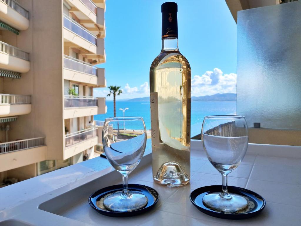 two wine glasses sitting on a counter with a bottle of wine at Saint-Raphaël-Front de Mer-WIFI-CLIM in Saint-Raphaël