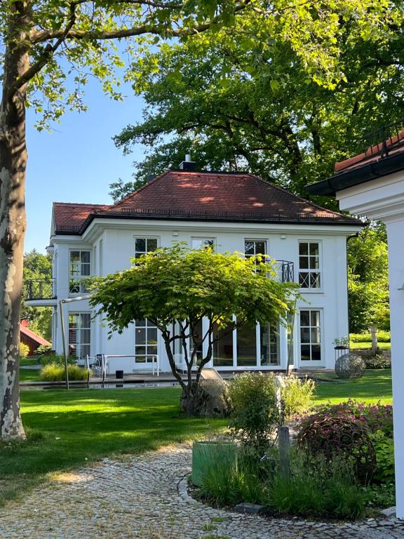 Una casa blanca con un árbol delante. en Herrenhaus - Starnberger See - Ammerland, en Münsing