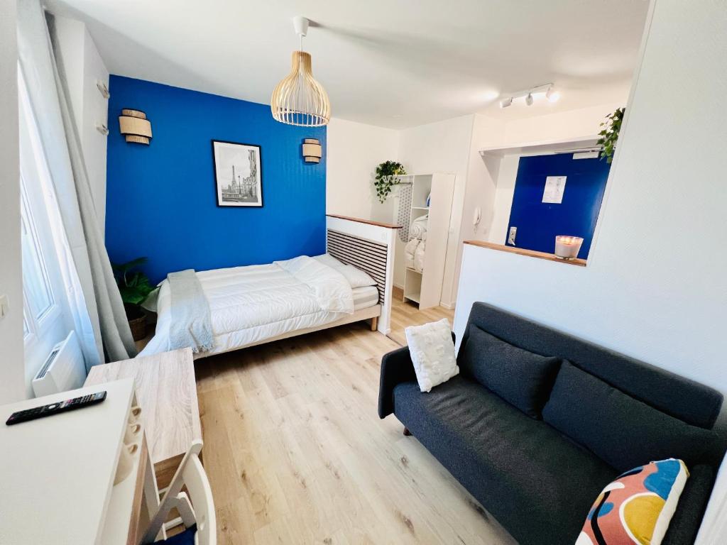 a living room with a couch and a blue wall at La vie en bleu - Studio proche de Paris in Charenton-le-Pont