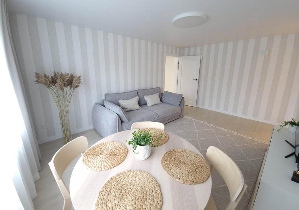 ein Wohnzimmer mit einem Tisch, Stühlen und einem Sofa in der Unterkunft Haustory Apartment in Klaipėda