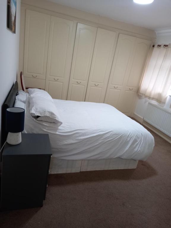a bedroom with a bed with white sheets and a table at Sandra in Streatham Vale
