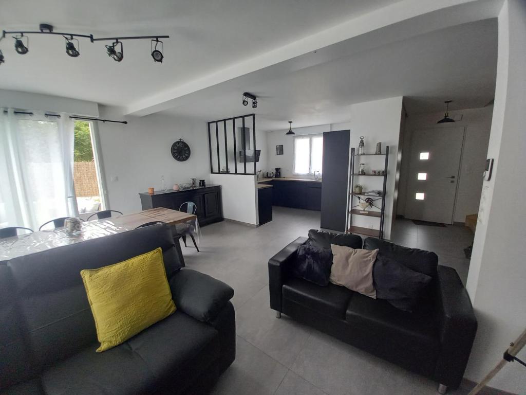 a living room with two black couches and a kitchen at Villa kerneing in Fouesnant