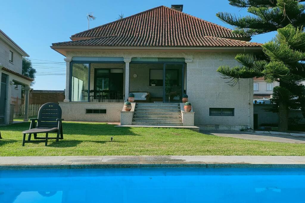una casa con panchina accanto a una piscina di Gran casa pareada con piscina en Vigo. Playa: 9min a Vigo