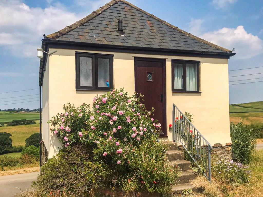 een klein huis met roze bloemen ervoor bij Weach Barton Granary in Bideford