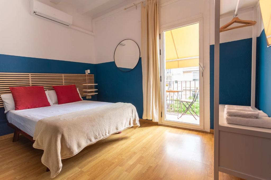 1 dormitorio con paredes azules y 1 cama con almohadas rojas en Mambo Tango, en Barcelona