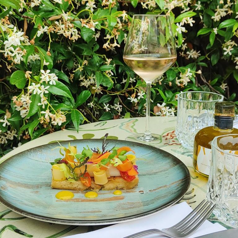 a plate of food on a table with a glass of wine at Hôtel La Pérouse Nice Baie des Anges in Nice