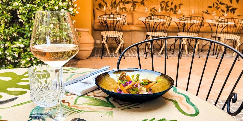 a bowl of food on a table next to a glass of wine at Hôtel La Pérouse Nice Baie des Anges in Nice