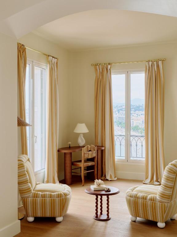 a living room with two chairs and a table at Hôtel La Pérouse Nice Baie des Anges in Nice
