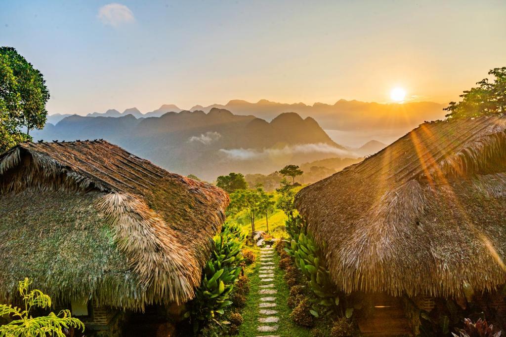 a group of huts with mountains in the background at Puluong Retreat in Pu Luong