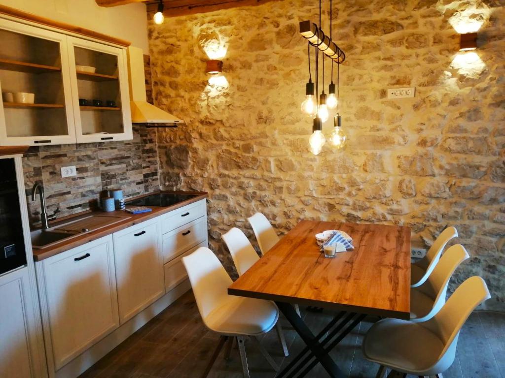 cocina con mesa de madera y sillas blancas en Apartments Dalmatian Stone House, en Turanj