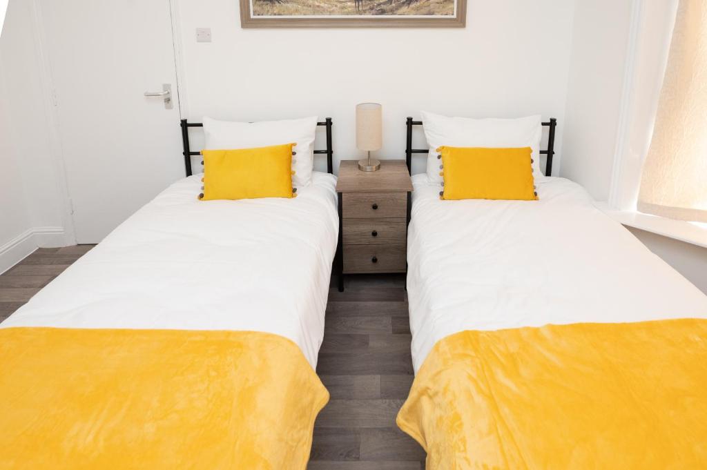2 camas en una habitación con almohadas amarillas en Brinton's Road - Modern Studio Apartments in City Centre en Southampton