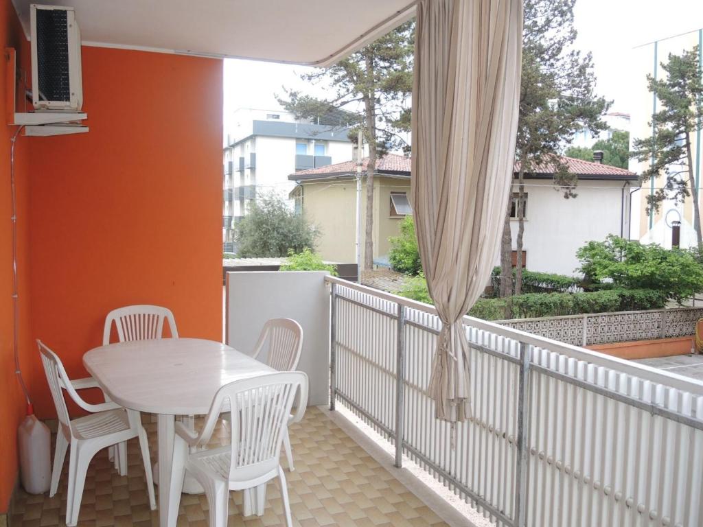 d'un balcon avec une table, des chaises et une fenêtre. dans l'établissement Warm two-room flat with terrace near the beach, à Bibione