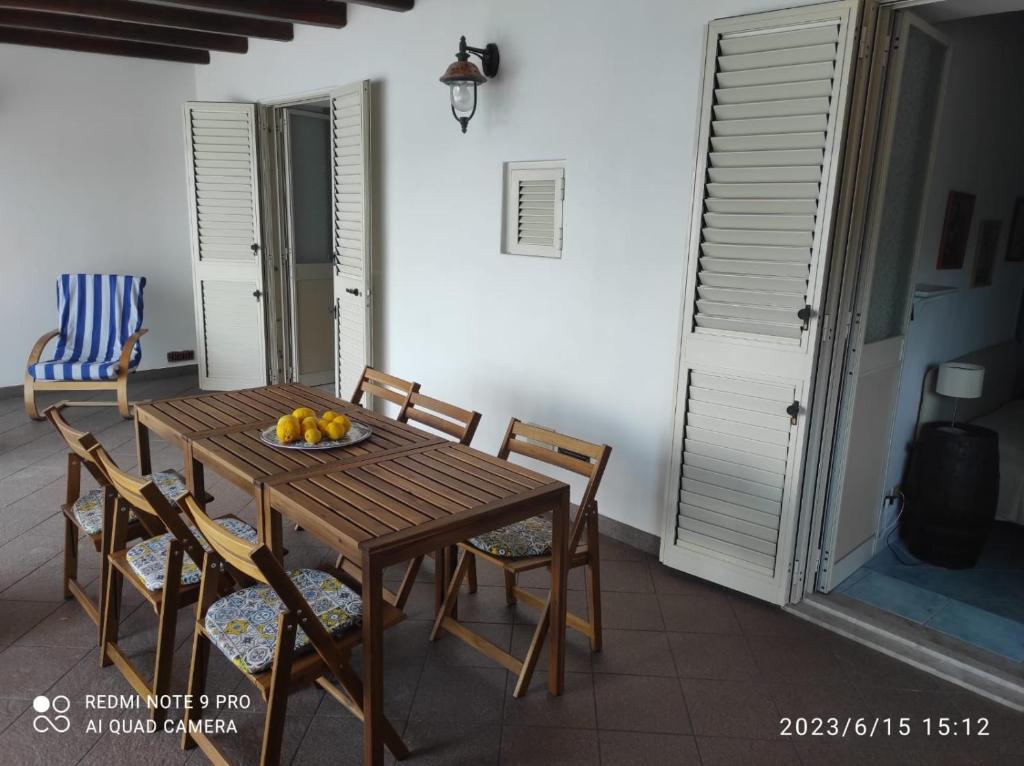 a wooden table with chairs and a bowl of fruit on it at Appartamento Rocche Rosse in Acquacalda