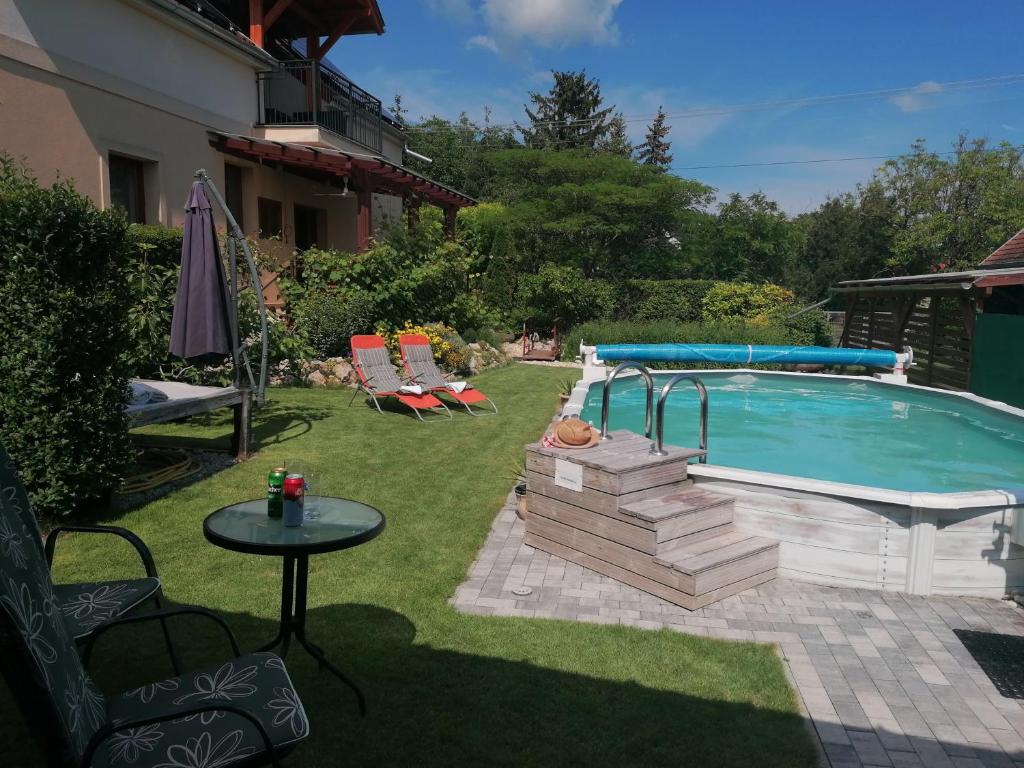 a swimming pool in a yard with a table and a table at Marianna Apartman in Gyenesdiás