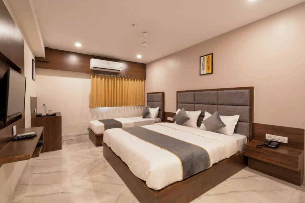 a bedroom with two beds and a flat screen tv at Hotel Royal 24 in Ahmedabad