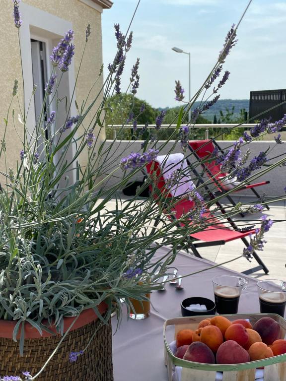 een tafel met een kom fruit en bloemen bij Val des Bruyères - gîte 15mn Pézenas avec terrasse et cour close - Parking privatif securisé - Wifi gratuit in Néffiès