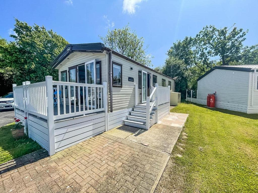 a white tiny house with a porch and stairs at Beautiful Caravan With Decking At Carlton Meres Holiday Park, Suffolk Ref 60022m in Saxmundham