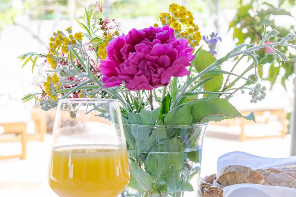 un jarrón lleno de flores junto a un vaso de zumo de naranja en B&B Arba, en Barbat na Rabu