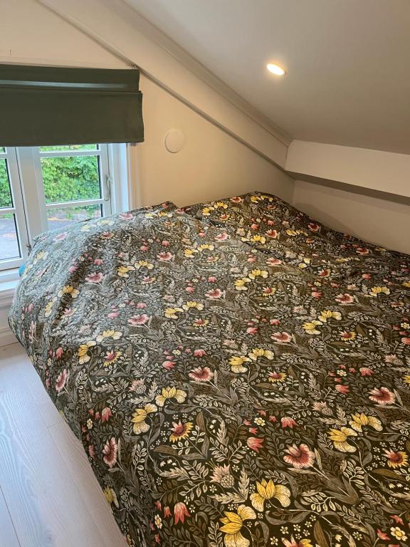 uma cama com um cobertor florido num quarto em Attefallshus Alingsås / Dammen. em Alingsås
