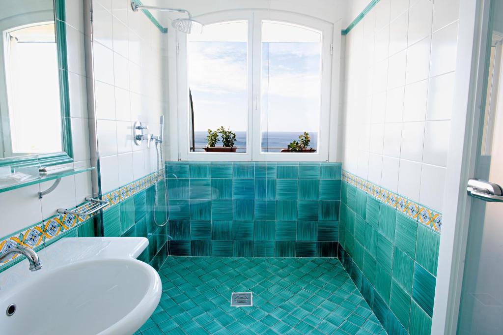 a bathroom with a tub and a sink and two windows at Hotel Villa Pandora in Maiori