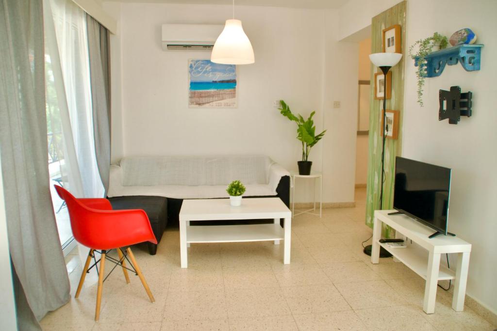 een woonkamer met een bank, een tafel en een tv bij Yiallos Village Apt. A101 in Menevi