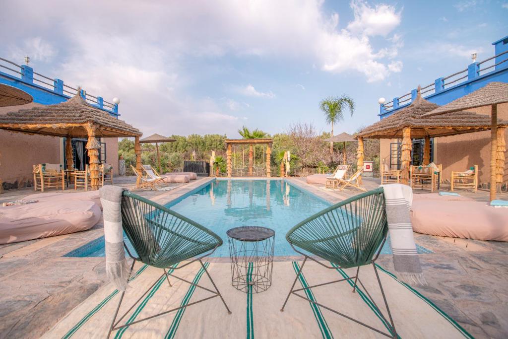 - une piscine avec 2 chaises et une table dans l'établissement La Fattoria Ecolodge, à Lalla Takerkoust