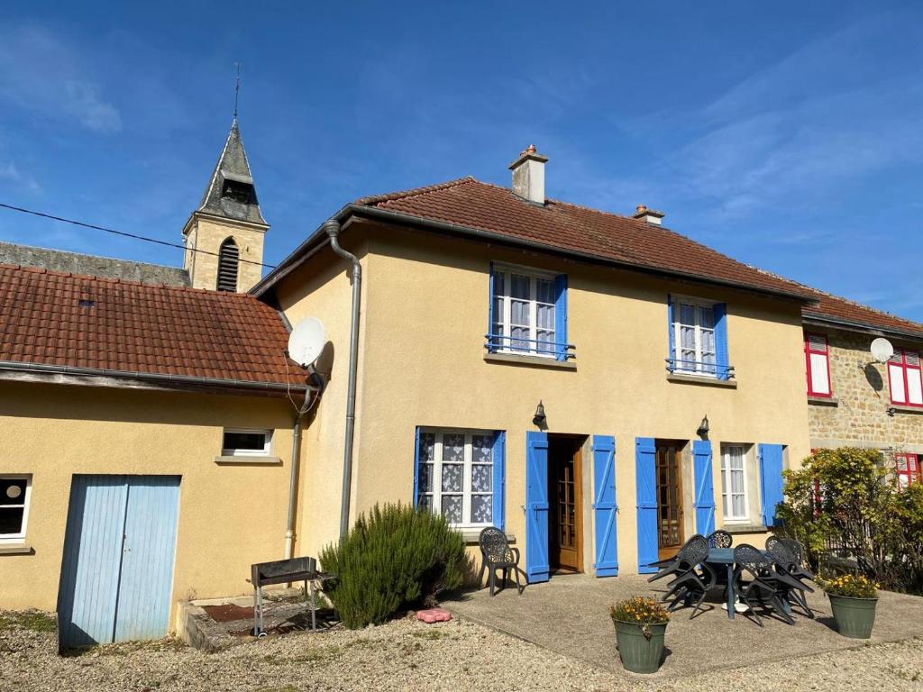 ein gelbes Haus mit blauen Türen und einem Kirchturm in der Unterkunft Melabelle in Malandry