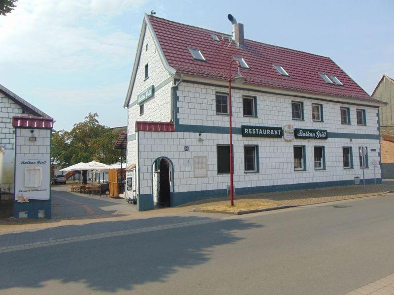 ein großes weißes Gebäude mit rotem Dach auf einer Straße in der Unterkunft Unseburg-Ferienwohnung 2 